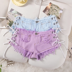 Dettaglio di pantaloncini in denim a vita bassa con lacci laterali e orli sfrangiati