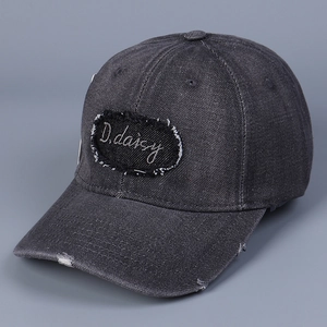 Dettaglio della toppa ricamata D.daisy sul cappello da baseball in denim grigio consumato