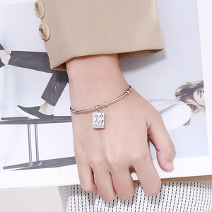 Detail of silver S925 cuff bracelet with engraved rectangular pendant on wrist
