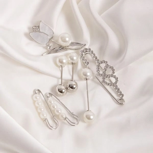 Detailed set of six elegant silver pins with pearls and tulips on white silk fabric