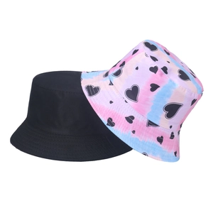 Detail view of a plain black cotton bucket hat and a pink tie-dye heart pattern sun hat