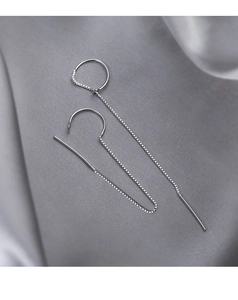Close-up of sleek silver tassel thread earrings on dark grey silk background
