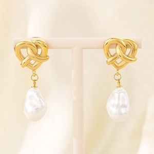 Detail of vintage heart-knot golden earrings featuring natural baroque pearl drops