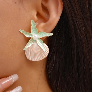 Close-up of beach-style starfish and shell earrings with pearls on a model ear