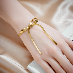 Gold bowknot snake bone bracelet on hand model with champagne silk background