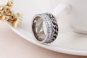 Detail of silver stainless steel rotating ring with curb chain and zircon inlays