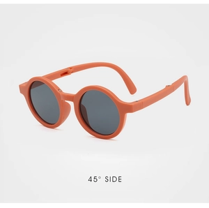 Detail view showing folding hinge on orange round children sunglasses with gray lenses