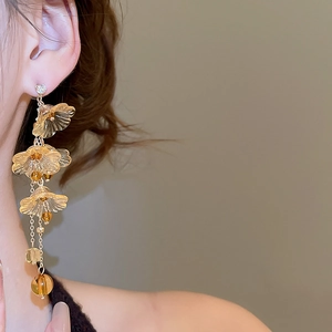 Detail of elegant tiered resin flower drop earrings in amber and champagne gold tones