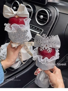 Detail of Christmas apple gift wrapping with sparkling snowflake sequins and silver bows