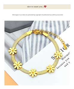 Detailed macro view of gold daisy flower charms on a stainless steel snake chain bracelet