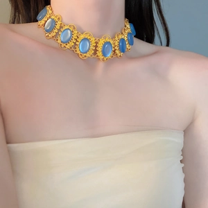 Detail of vintage palace style choker with gold hollowed frames and blue oval cat-eye stones