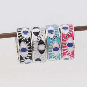 Macro detail of four colorful enamel evil eye rings on a wooden display stick