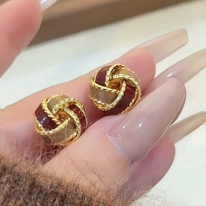Detailed close-up of retro knotted stud earrings with burgundy and beige enamel finish