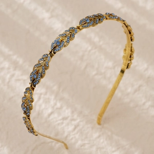 Macro shot of gold leaf-shaped headband featuring elegant blue rhinestones for wedding
