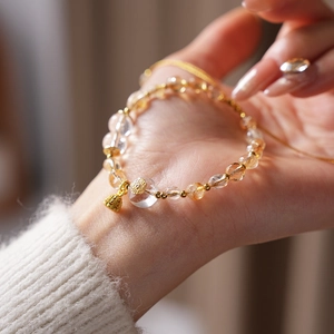 Detail of beaded citrine bracelet with gold metal spacer beads and hollow bell charm