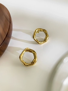 Detailed close-up of gold irregular wavy hoop earrings on a clean minimalist background
