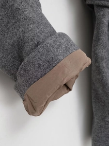 Detail of grey woolen coat cuff with coffee satin lining and premium stitching craftsmanship