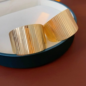 Detailed view of wide gold rings with vertical pleat texture on jewelry box