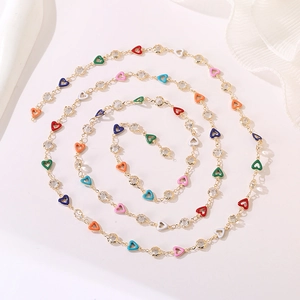 Detailed view of long gold chain necklace with colorful enamel hearts and sparkling crystals