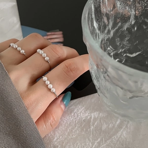 Elegant silver open ring with four delicate pearls on fingers for a layered jewelry look