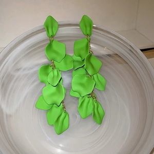 Detail of green petal tassel earrings featuring layered long drop design in a glass bowl