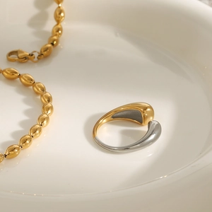 Detailed view of two-tone titanium steel ring and gold bean chain on ceramic