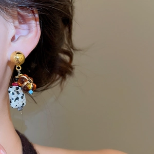 Close-up of vintage beaded earrings with natural Dalmatian stone worn by a model