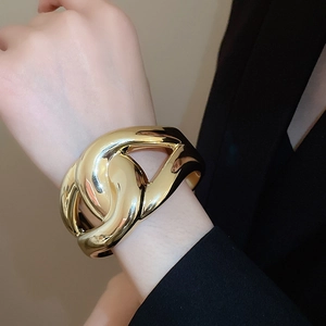 Detailed view of wide chunky gold interlocking link cuff bracelet worn on wrist
