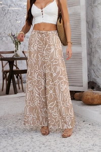 Détail du pantalon large kaki avec imprimé abstrait blanc et taille élastique sous la lumière