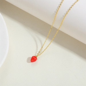 Macro shot of 14k gold strawberry pendant necklace on minimalist white stone