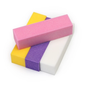 Detail of four colorful nail buffer blocks in pink yellow purple and white foam