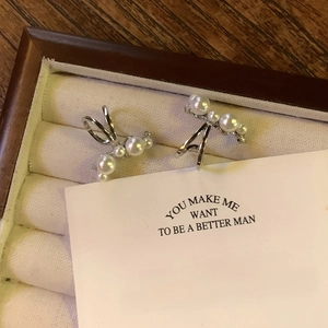 Macro detail of elegant silver pearl ear cuffs with zircons on a velvet jewelry box