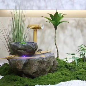 Detail of Zen indoor water fountain with bamboo spout, faux moss, and purple LED lighting