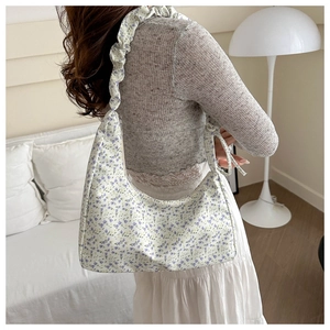 Détail du sac sous le bras à fleurs mauves avec bandoulière à volants sur modèle