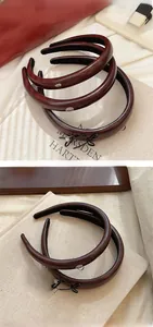 Close-up of wine red PU leather headband with micro metal charms and black bow detail