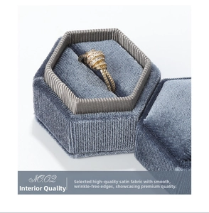 Detailed view of a hexagonal blue-grey velvet jewelry box with a satin-lined ring slot