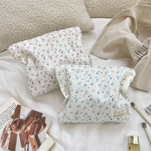 Close-up of floral and cherry pattern cotton makeup bags on a soft bed setting