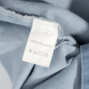 Vue détaillée de l'étiquette 100% polyester et de la texture denim bleue de la robe