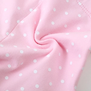 Detail view of pink cotton fabric with white polka dots and high-quality double-needle stitching