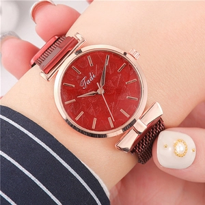 Close-up of red dial quartz watch with leaf pattern and rose gold mesh strap on wrist
