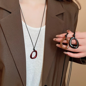 Détail des pendentifs géométriques irréguliers en émail rouge, marron et noir