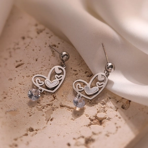 Elegant silver heart-shaped earrings with round clear zircon drop on a textured stone surface