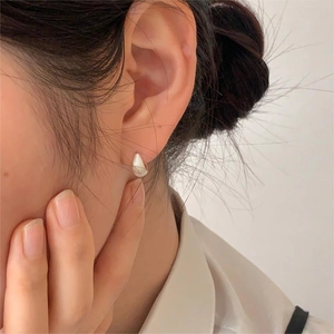 Close-up of minimalist S925 sterling silver hoop earrings with shell texture on model