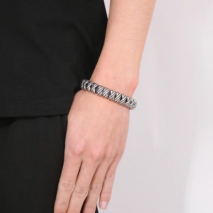 Close-up of men's silver woven titanium steel bracelet worn on wrist with twisted rope design