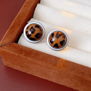 Gros plan de boucles d'oreilles rondes léopard sur un support en velours marron