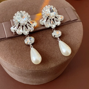 Detail of crystal flower earrings with pear-shaped pearls on a brown velvet jewelry box