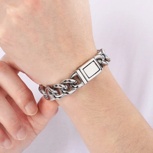 Close-up of high-polish silver stainless steel Cuban and pig nose link bracelet on wrist