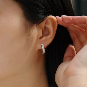 Close-up of minimalist silver hoop earrings featuring double rows of moissanite crystals