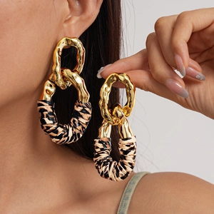 Exaggerated metal and leopard print geometric oval drop earrings worn by a model
