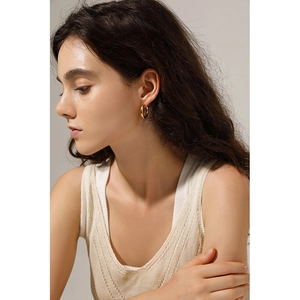 Close-up of minimalist gold-plated hoop earrings worn to show texture and scale